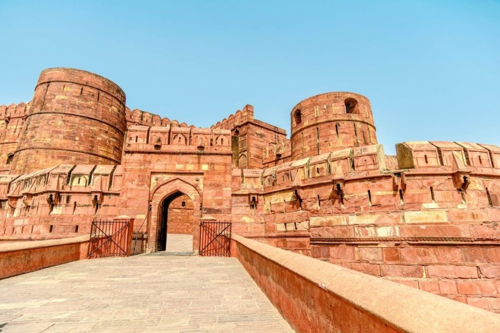 Main entrance of Agra Fort showcasing red sandstone walls and Mughal architecture under a clear blue sky.