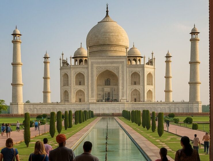 Tourists walking along the Taj Mahal’s reflecting pool toward the monument on a clear day.