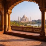 View of the Taj Mahal seen through red sandstone arches inside Agra Fort, showcasing Mughal architecture with warm daylight, historical atmosphere, and the Yamuna River flowing in the background.