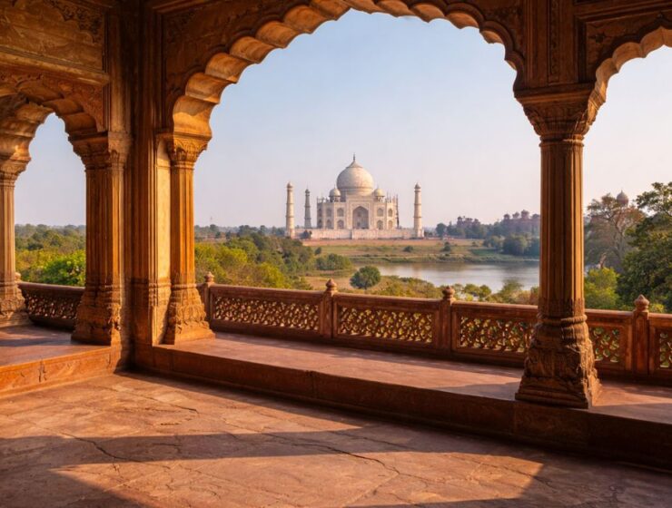 View of the Taj Mahal seen through red sandstone arches inside Agra Fort, showcasing Mughal architecture with warm daylight, historical atmosphere, and the Yamuna River flowing in the background.